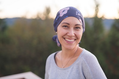 Cancer patient wearing headscarf smiling outdoors after high-dose vitamin C IV therapy
